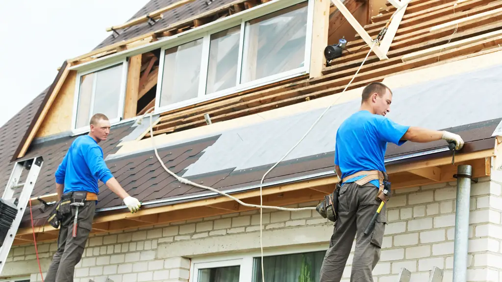 Two ABCO roofers working on an open residential roof deck mid tear-off