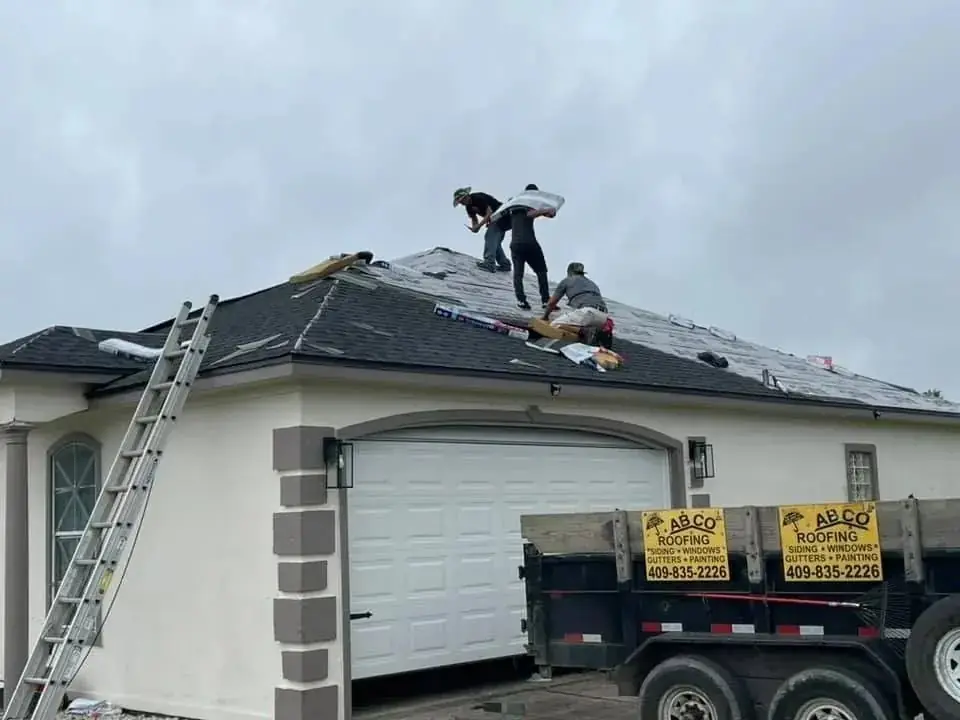 ABCO crew installing a new shingle roof on a garage, ABCO trailer parked alongside